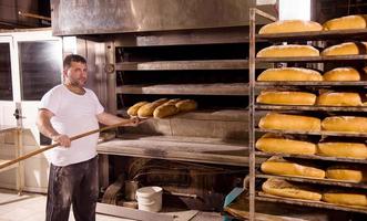 trabajador de panadería sacando panes recién horneados foto