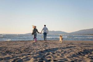 pareja con perro divirtiéndose en la playa el día del otoño foto