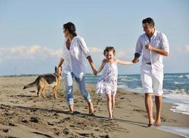 familia feliz jugando con el perro en la playa foto