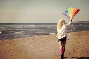 Young Woman with kite at beach on autumn day photo