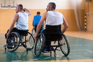 handicapped war veterans in wheelchairs with professional equipment play basketball match in the hall.the concept of sports with disabilities photo