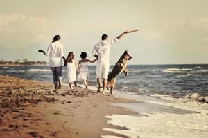 happy family playing with dog on beach photo