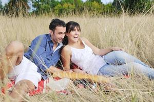 pareja feliz disfrutando de un picnic en el campo en hierba larga foto