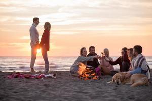 Couple enjoying with friends at sunset on the beach photo