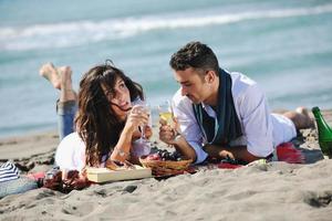 pareja joven disfrutando de un picnic en la playa foto