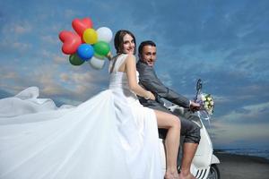 just married couple on the beach ride white scooter photo