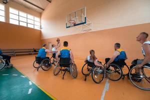 Disabled War veterans mixed race and age basketball teams in wheelchairs playing a training match in a sports gym hall. Handicapped people rehabilitation and inclusion concept photo