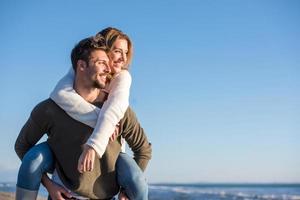 pareja divirtiéndose en la playa durante el otoño foto