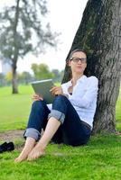 hermosa mujer joven con tableta en el parque foto