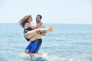 feliz pareja joven tiene tiempo romántico en la playa foto