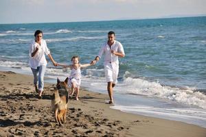 happy family playing with dog on beach photo