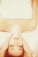 mujer recibiendo masaje facial y de cabeza en el salón de spa