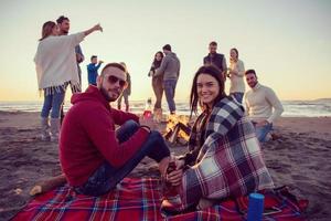 Couple enjoying with friends at sunset on the beach photo