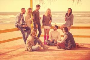 grupo de amigos divirtiéndose el día de otoño en la playa foto