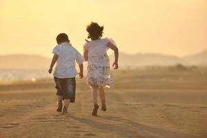 familia joven feliz divertirse en la playa al atardecer foto