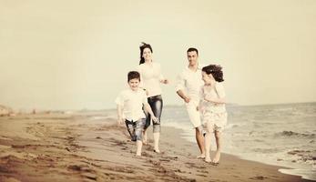 familia joven feliz divertirse en la playa foto