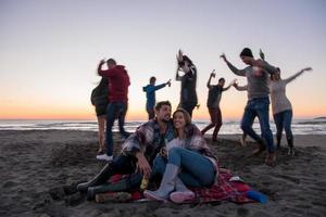 pareja disfrutando con amigos al atardecer en la playa foto