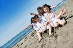 Grupo de niños felices jugando en la playa foto