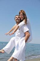 feliz pareja joven divertirse en la playa foto