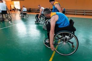 Disabled War veterans mixed race and age basketball teams in wheelchairs playing a training match in a sports gym hall. Handicapped people rehabilitation and inclusion concept photo