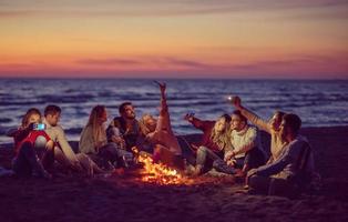 a group of friends enjoying bonfire on beach photo