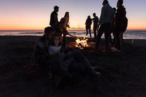 Couple enjoying bonfire with friends on beach photo