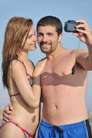 feliz pareja joven enamorada tomando fotos en la playa