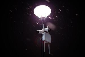cámaras inalámbricas en poste de luz de invierno nocturno con nieve y enfoque selectivo foto