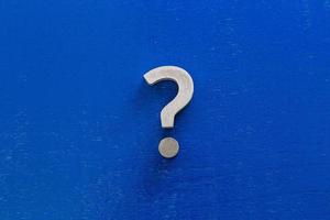 A question sign on center of blue painted board - flat lay conept photo