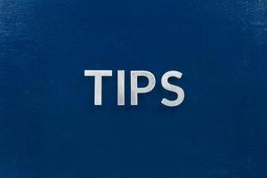 the word tips laid with silver letters on blue color surface photo