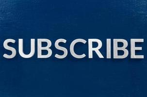 the word subscribe laid with aluminium letters on blue paint board background photo