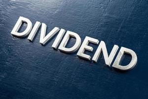 the word dividend laid by volumetric silver metal letters on gloss painted board background with selective focus photo