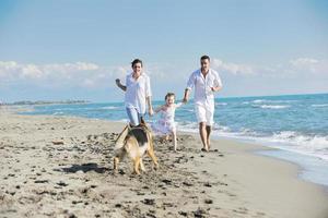 happy family playing with dog on beach photo