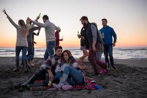 pareja disfrutando con amigos al atardecer en la playa foto