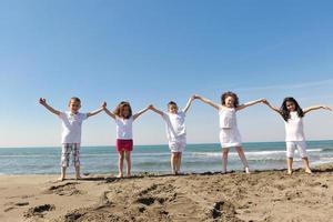 Grupo de niños felices jugando en la playa foto