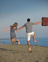 pareja en la playa con bolsa de viaje foto