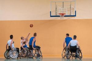 Disabled War veterans mixed race opposing basketball teams in wheelchairs photographed in action while playing an important match in a modern hall. photo