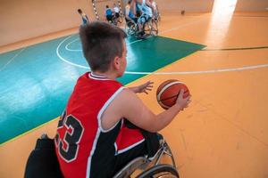 the boy sits in a wheelchair and prepares for the basketball start of the game in the big arena. Selective focus photo