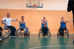 the selector of the basketball team with a disability stands in front of the players and shows them the stretching exercises before the start of training photo