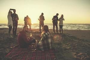 Couple enjoying with friends at sunset on the beach photo