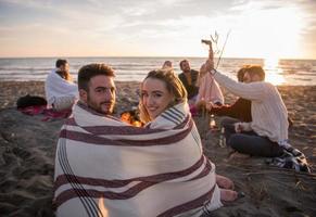 Couple enjoying with friends at sunset on the beach photo