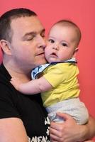 portrait of happy young father holding baby isolated on red photo