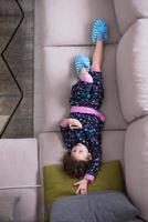 top view of little girl using a smartphone on the sofa photo