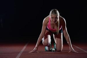 woman  sprinter leaving starting blocks photo