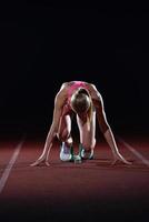 woman  sprinter leaving starting blocks photo