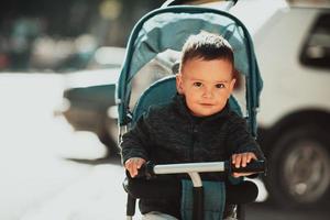 Sweet baby boy in a stroller bicycle outdoors. Little child in a pram. Infant kid in a pushchair. Spring walks with kids. photo