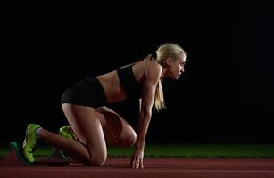 woman  sprinter leaving starting blocks photo