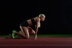 woman  sprinter leaving starting blocks photo