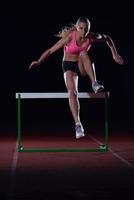 woman athlete jumping over a hurdles photo