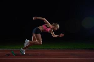 woman  sprinter leaving starting blocks photo